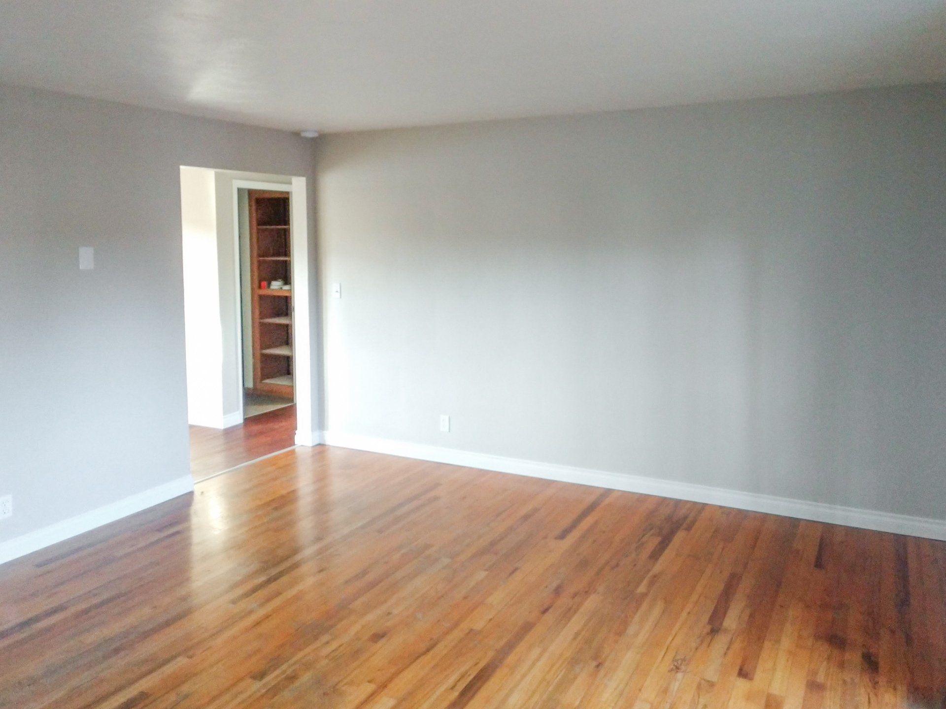 An empty room with hardwood floors and gray walls