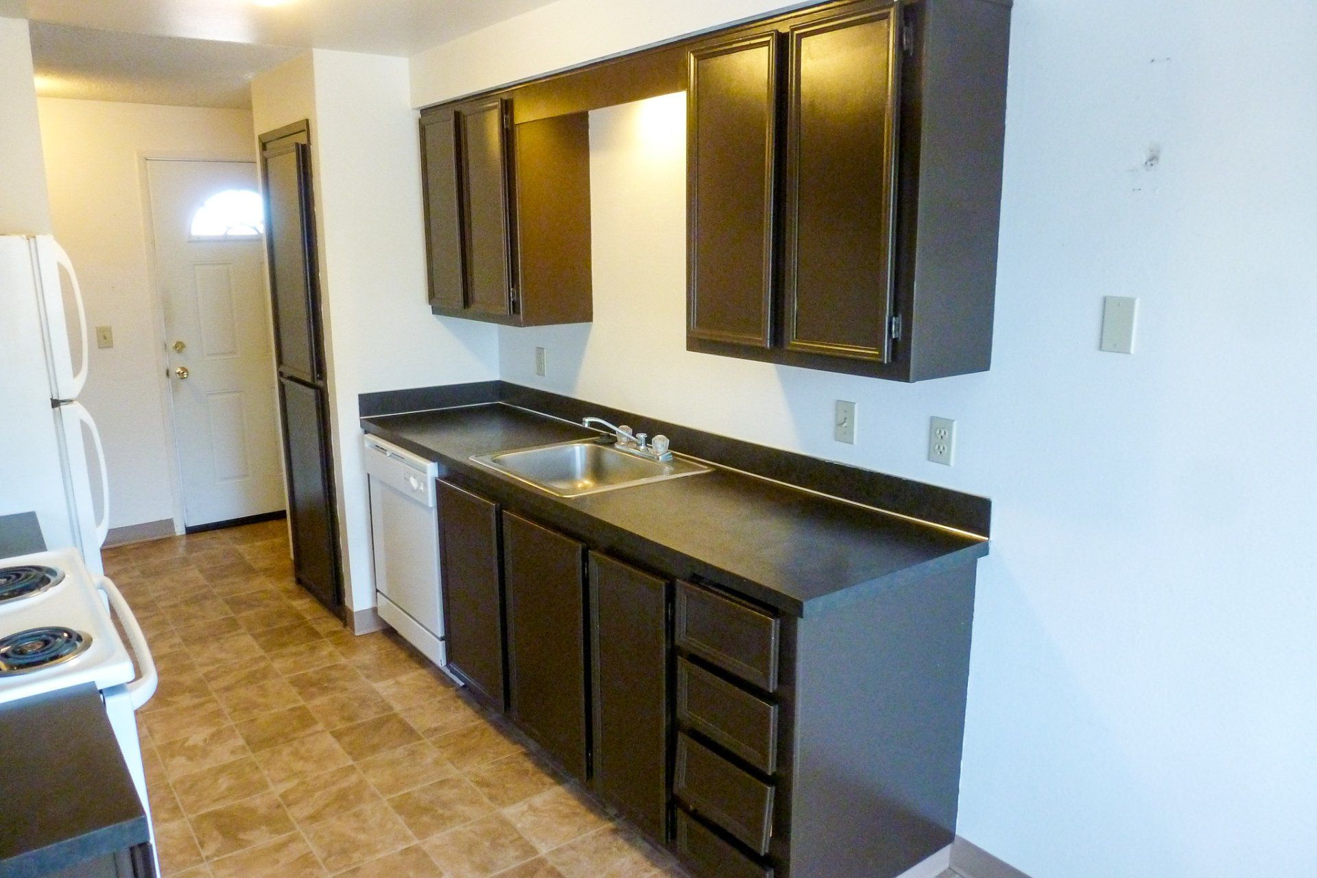 A kitchen with brown cabinets and a white refrigerator