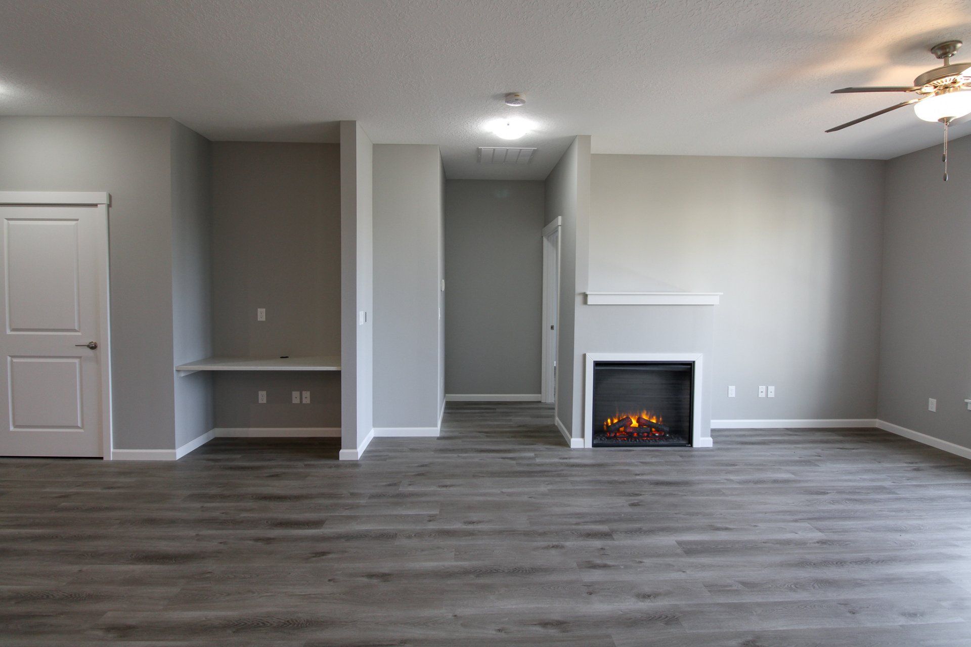 An empty living room with a fireplace and a ceiling fan.