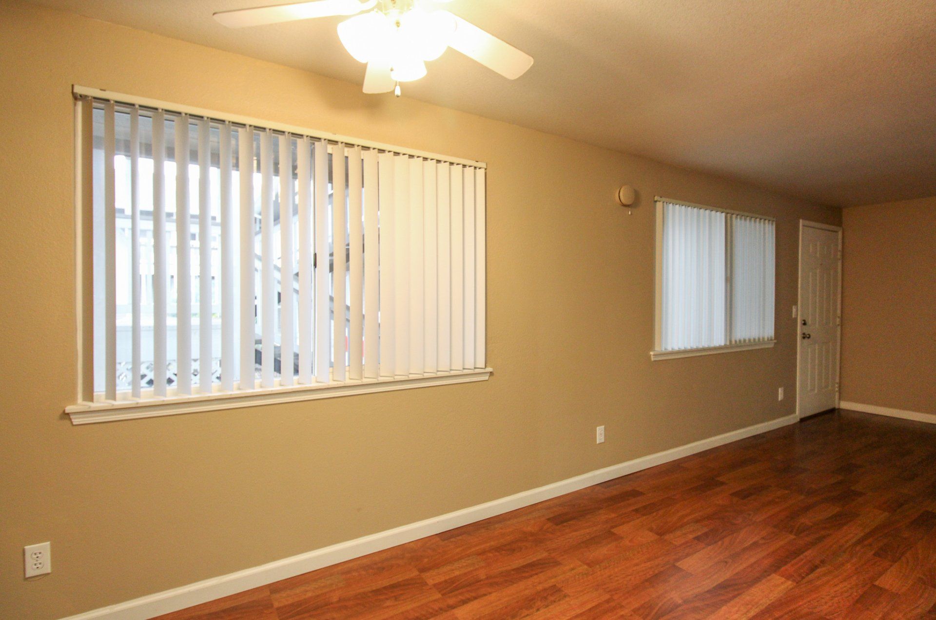 An empty living room with hardwood floors and a ceiling fan
