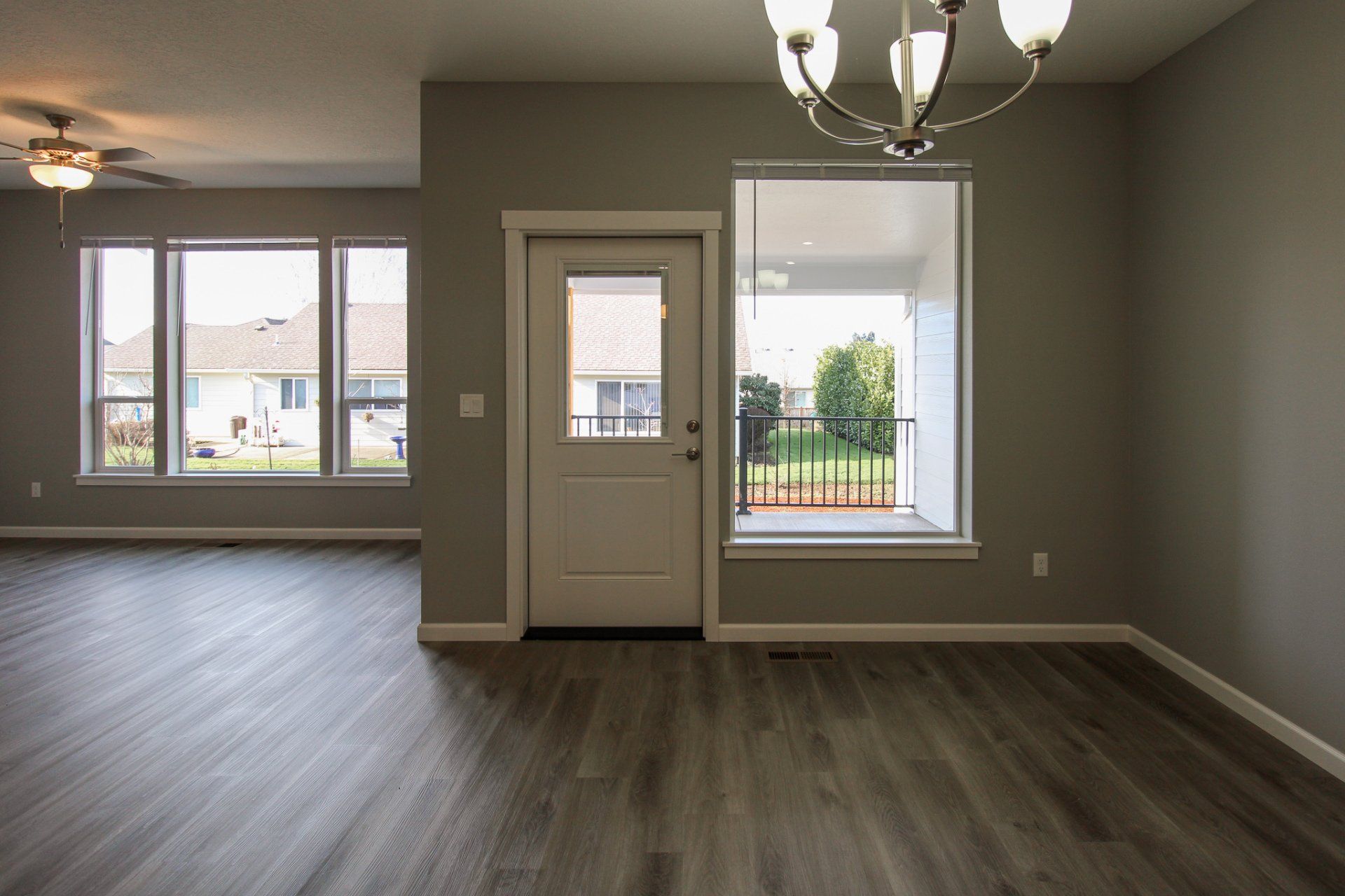 An empty living room with hardwood floors and a chandelier.