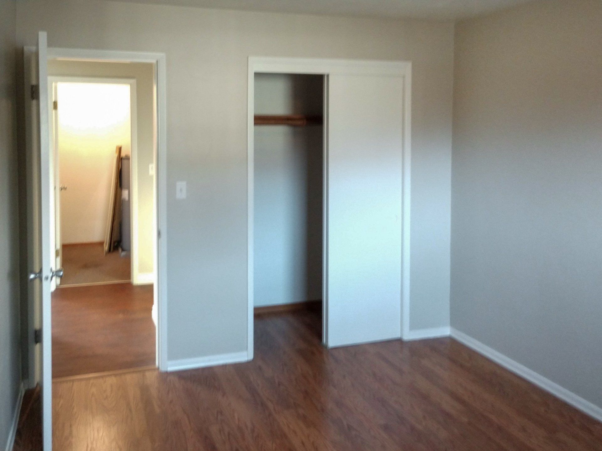 An empty bedroom with hardwood floors and a closet.