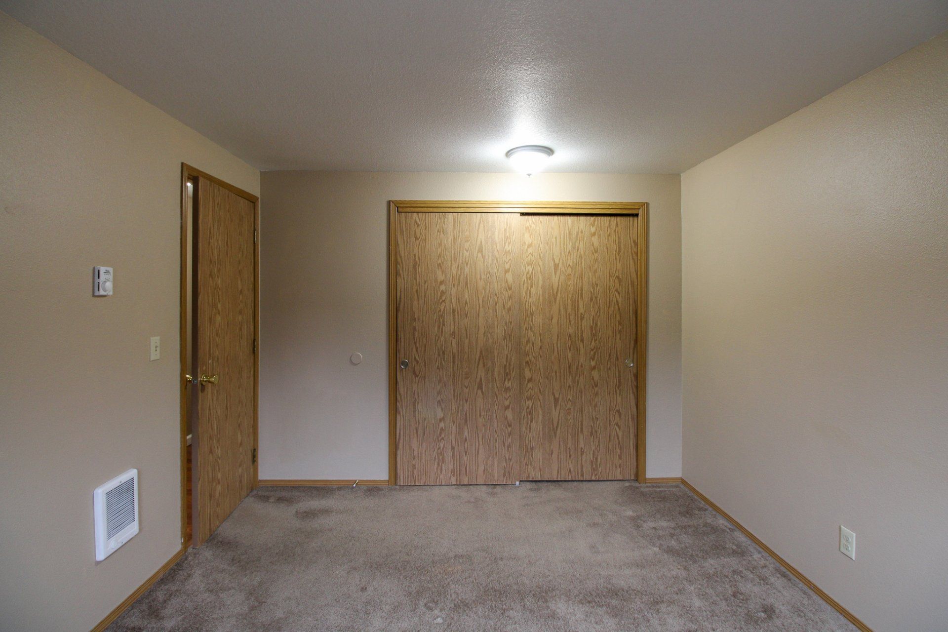 An empty room with a carpeted floor and wooden doors.