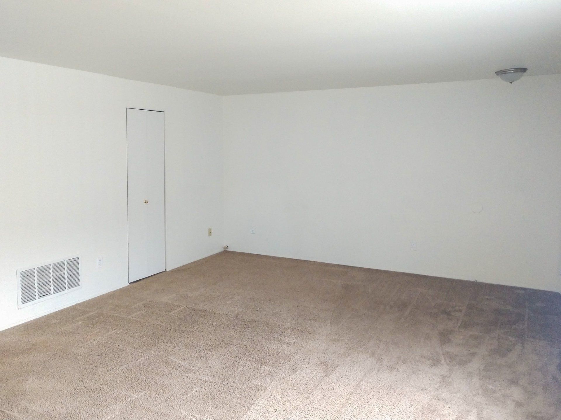 An empty room with a carpeted floor and white walls