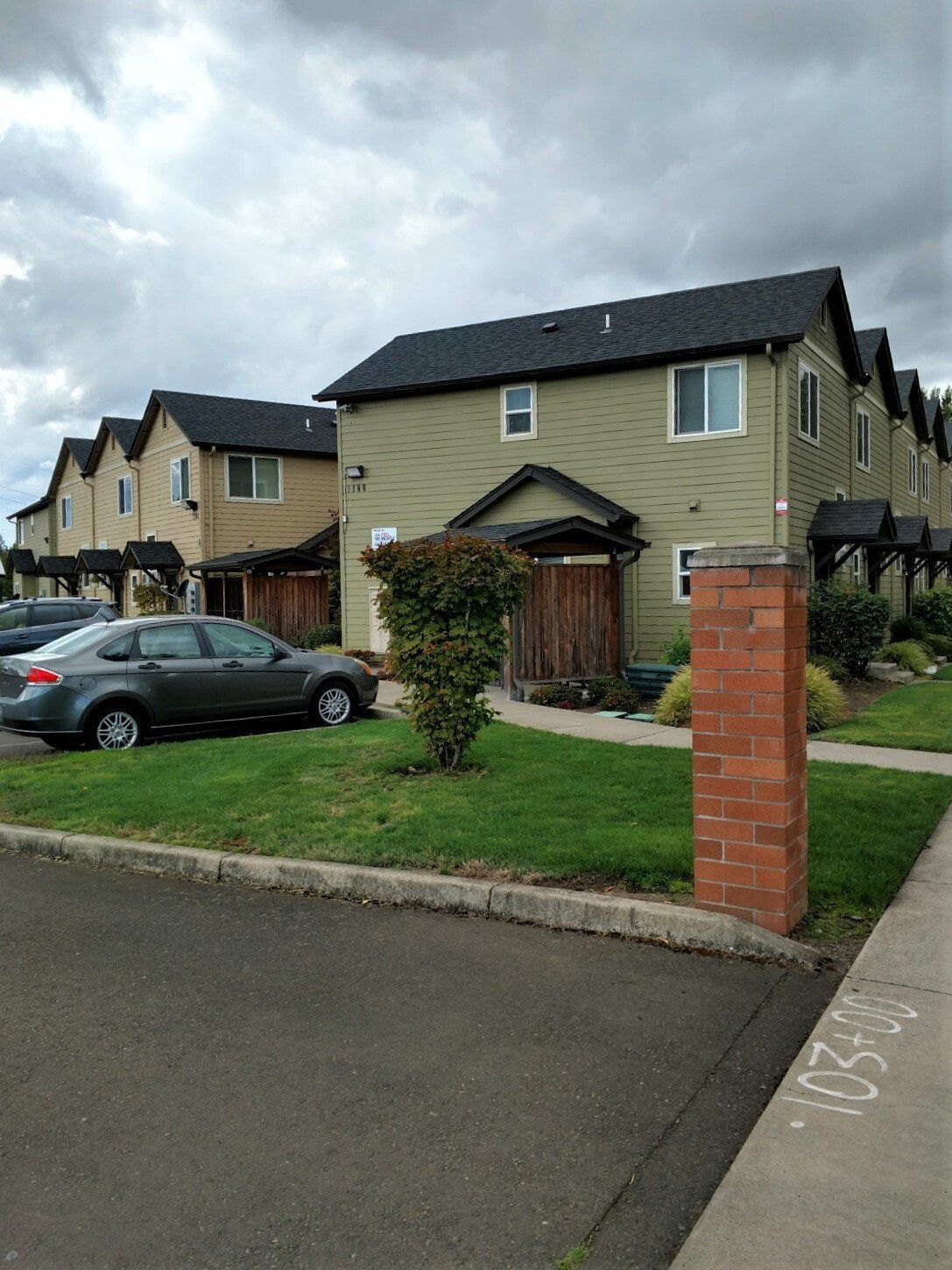 A row of houses with cars parked in front of them.