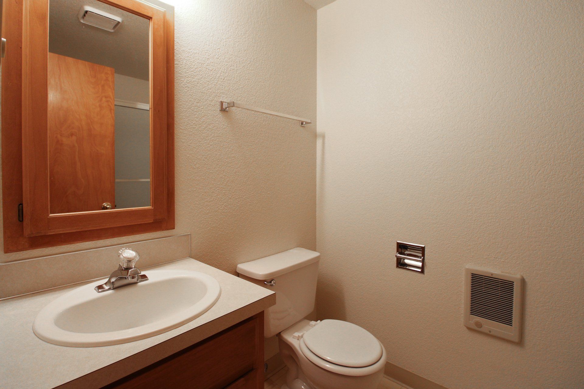 A bathroom with a toilet a sink and a mirror
