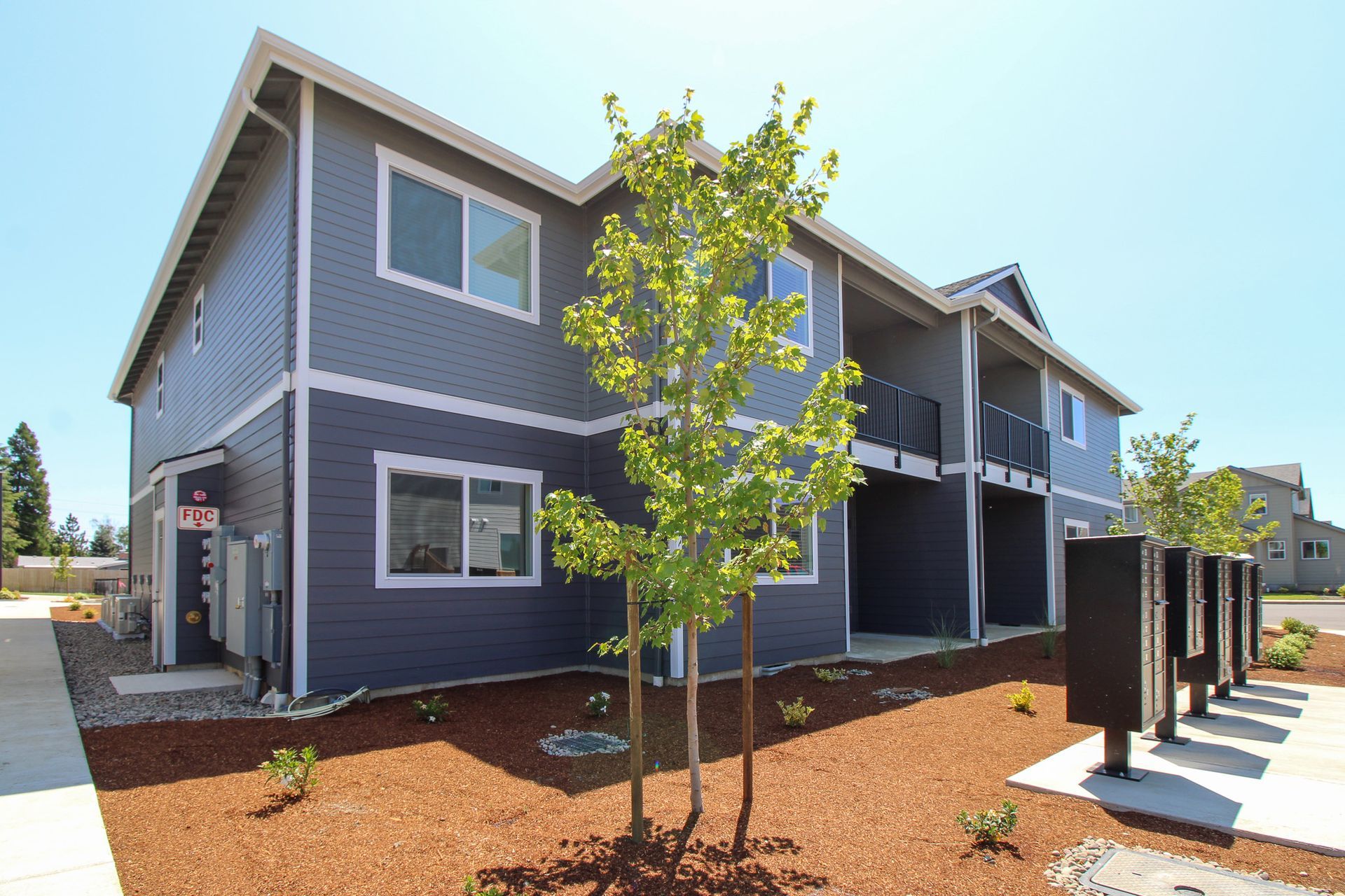 A gray apartment building with a tree in front of it