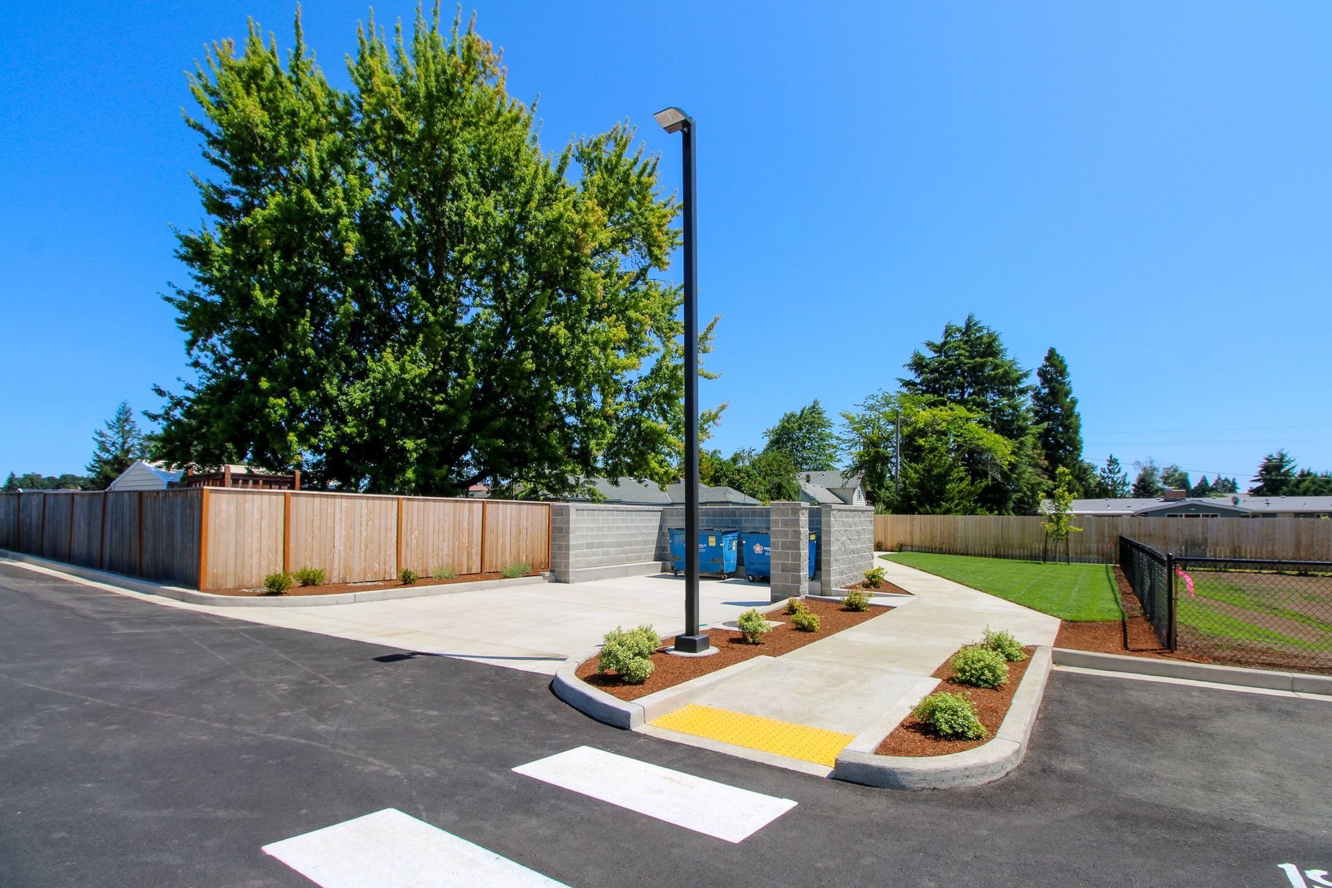 A parking lot with a fence and trees in the background
