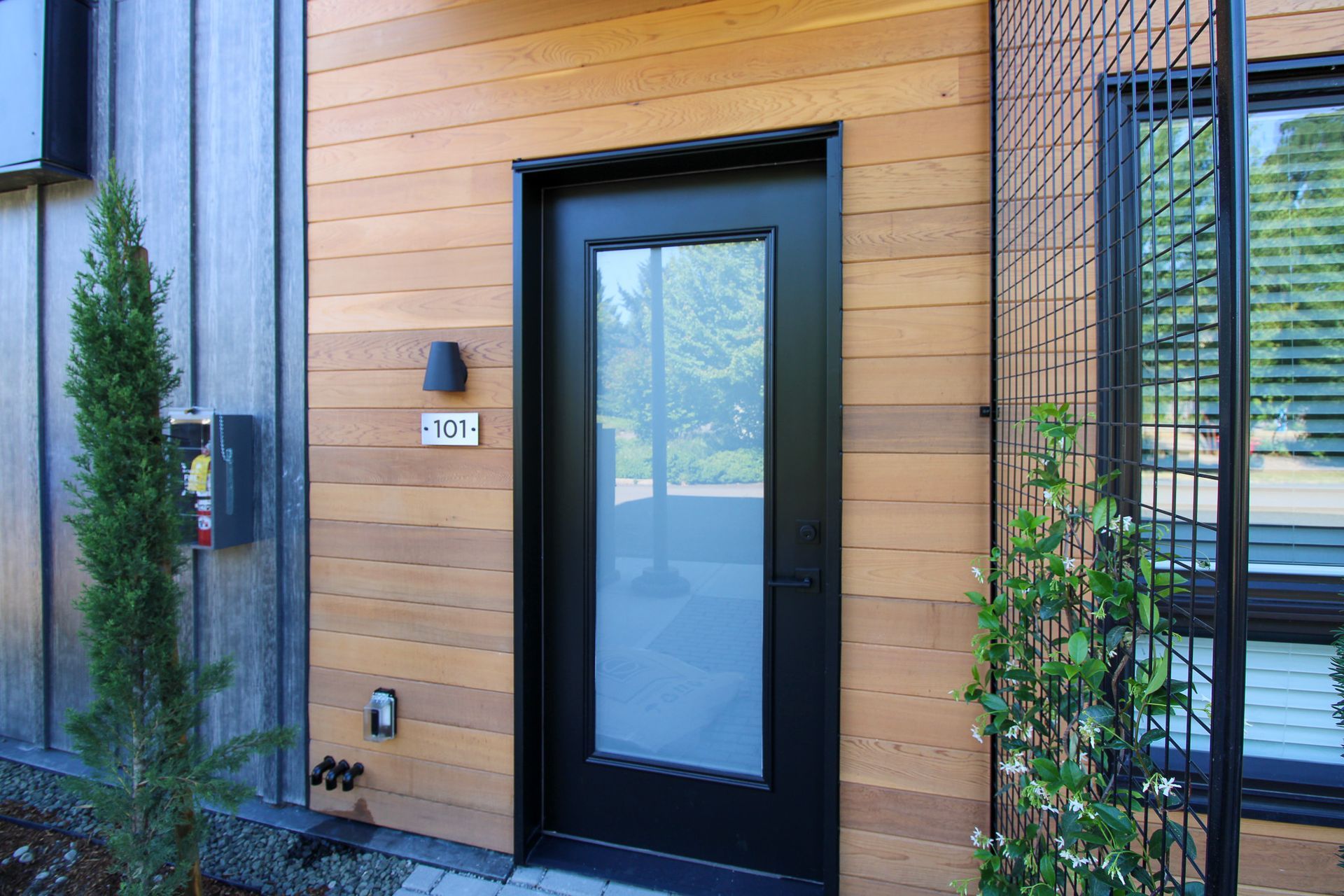 A black door with a glass window is on the side of a wooden building.