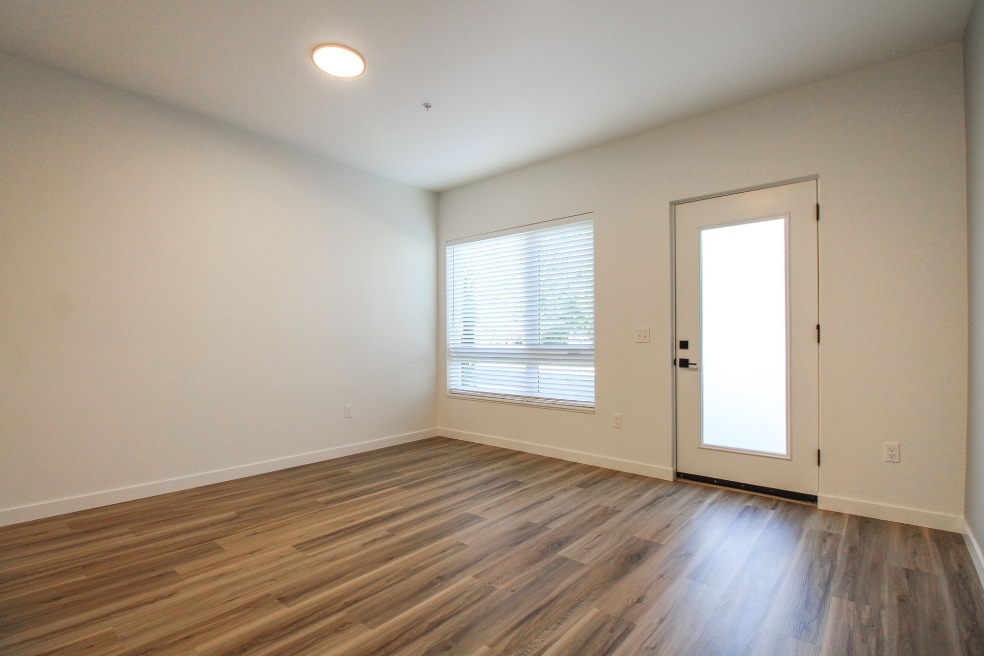 An empty living room with hardwood floors and a window.