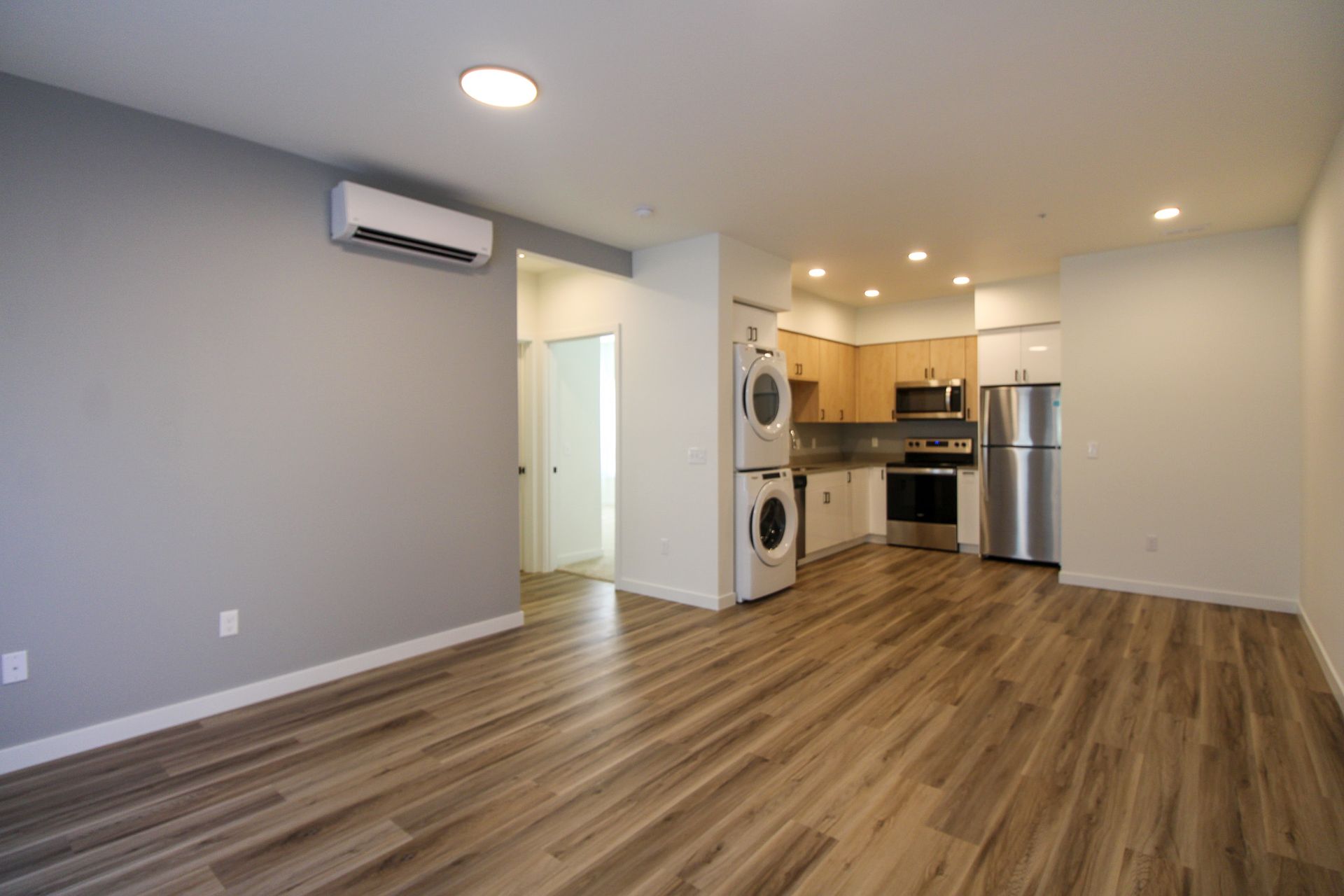 A living room with hardwood floors and a kitchen in the background.