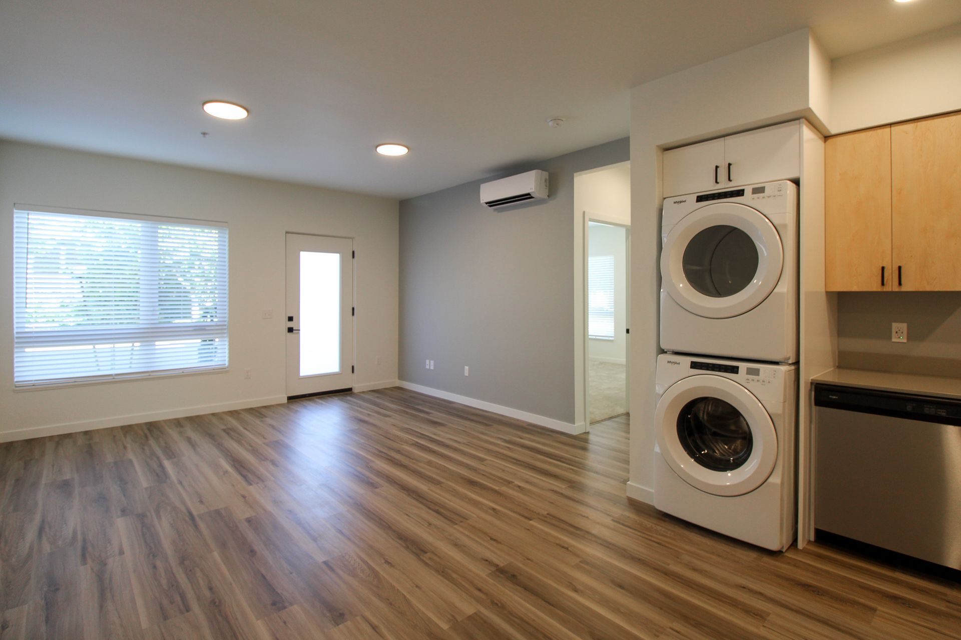 A living room with a washer and dryer stacked on top of each other.