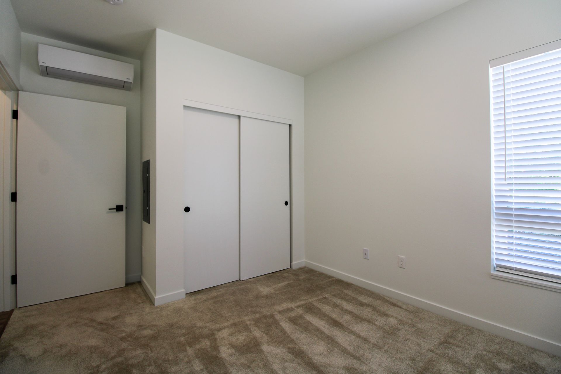 An empty bedroom with a closet and a window.
