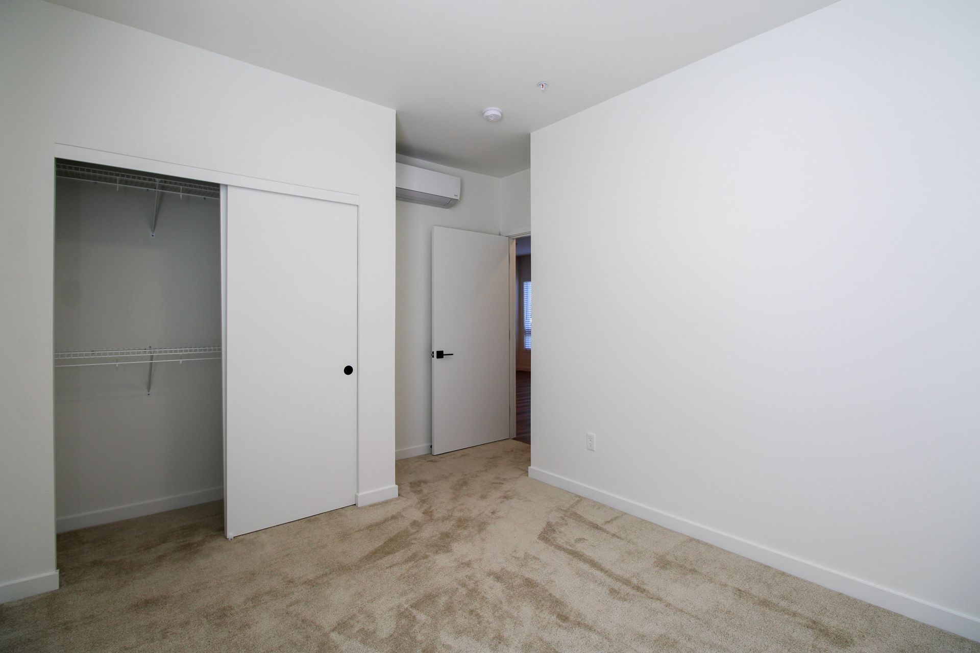 An empty bedroom with a walk in closet and white walls.