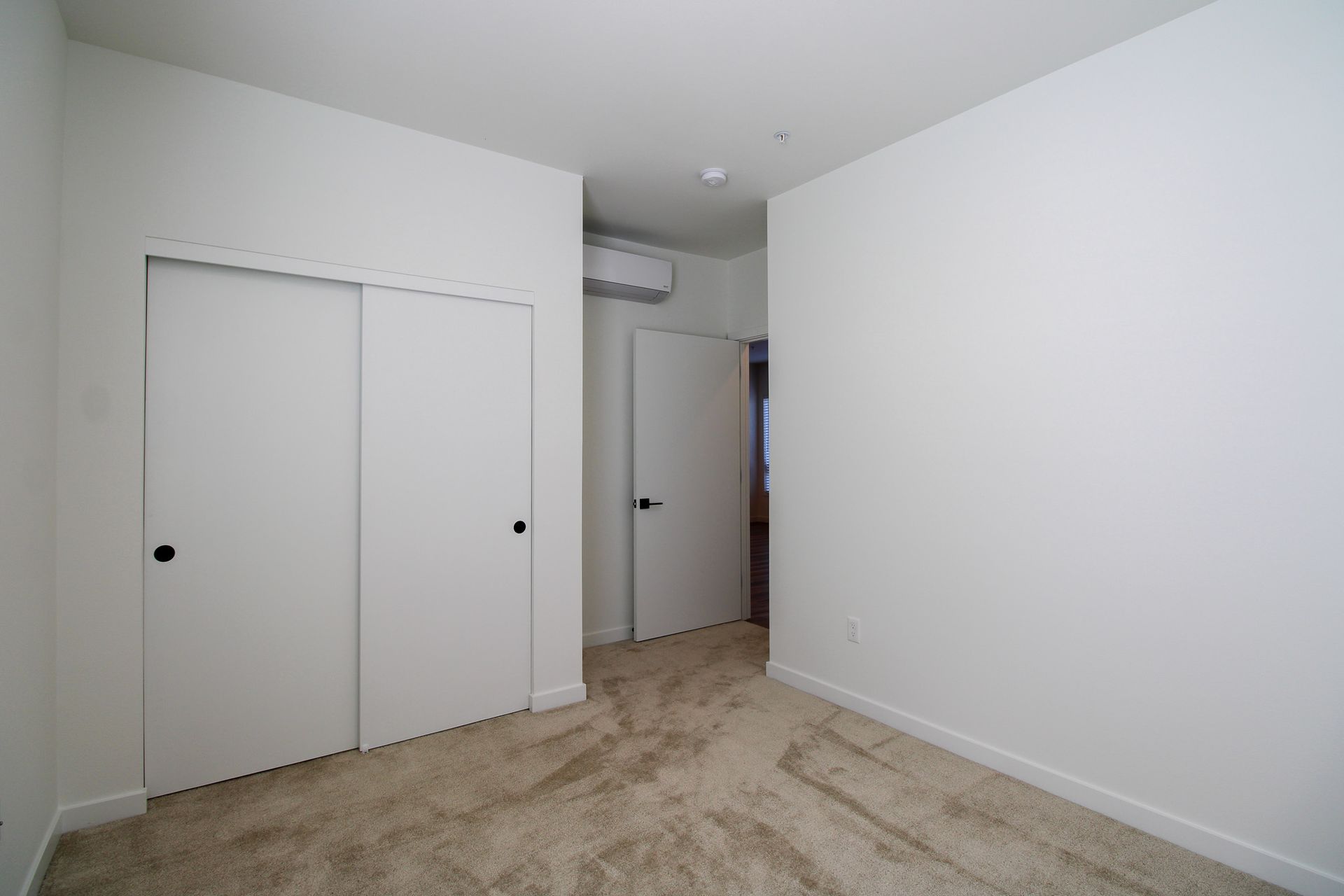 An empty bedroom with two closets and a carpeted floor.