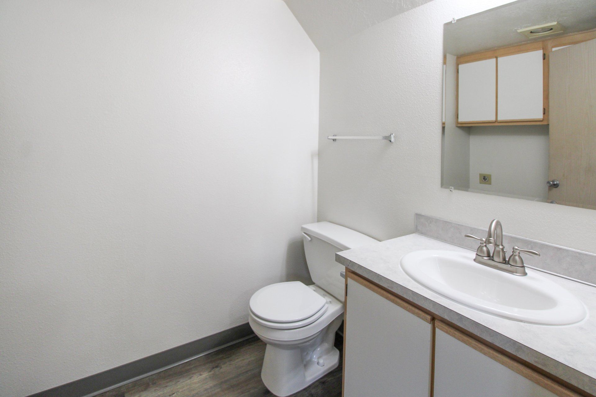 A bathroom with a toilet , sink and mirror.