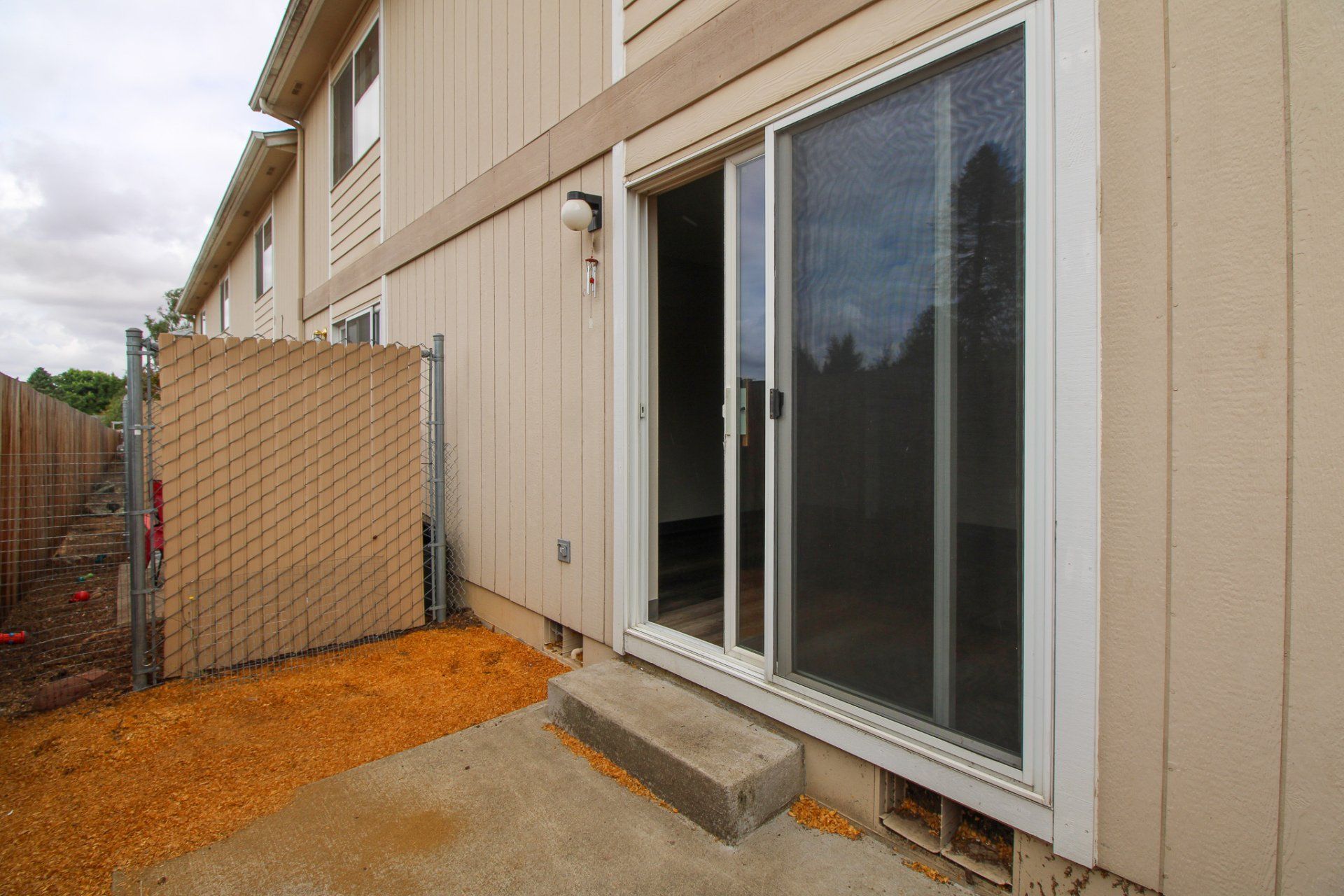 There is a sliding glass door in the backyard of a house.