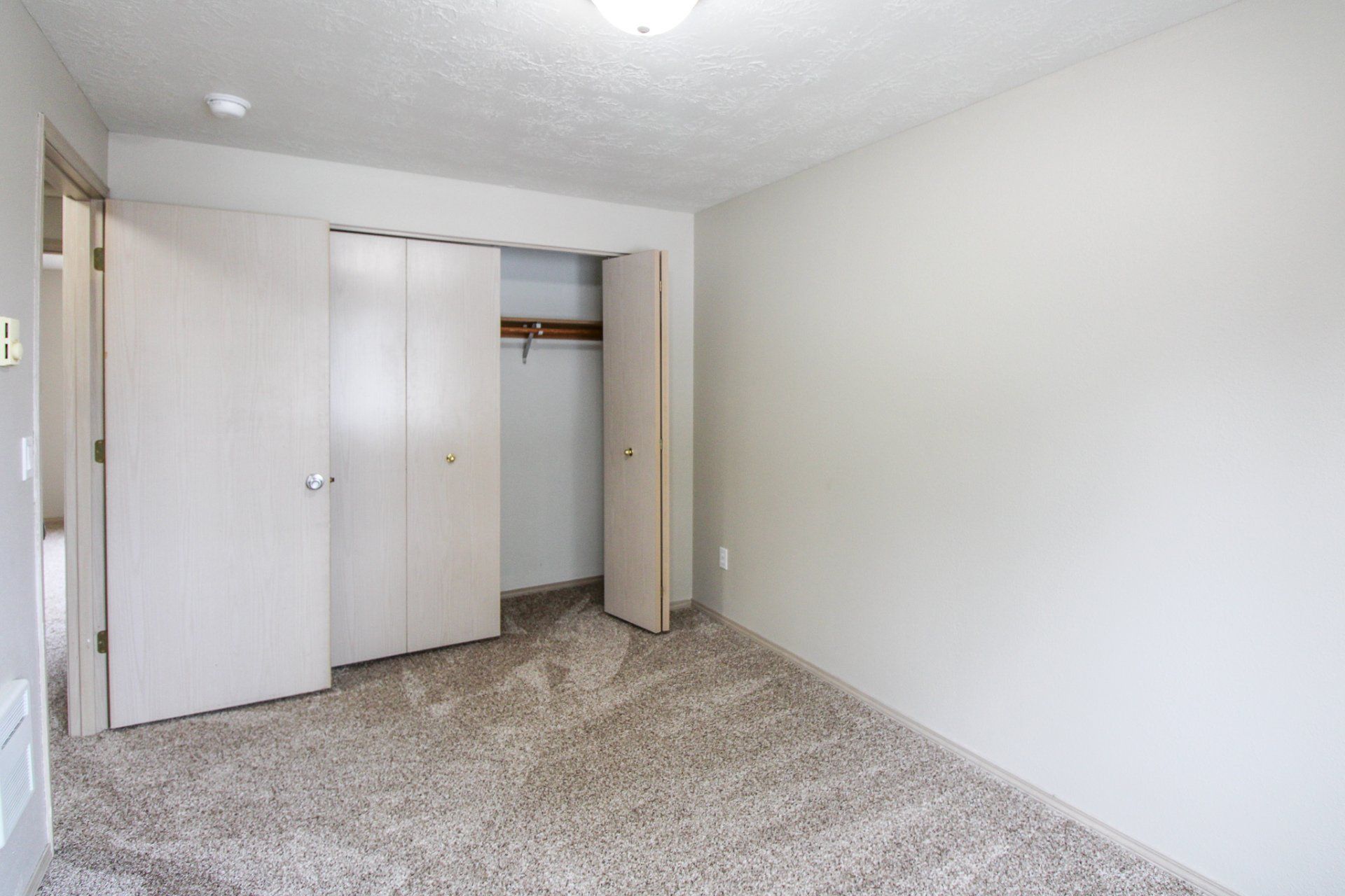 An empty bedroom with a closet and a carpeted floor