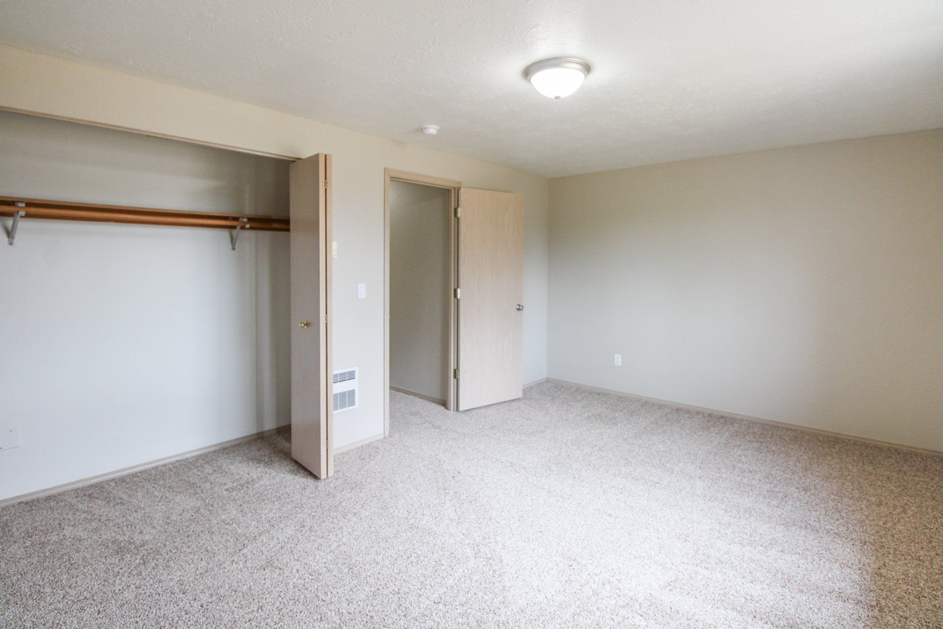 An empty bedroom with a closet and a light on the ceiling.