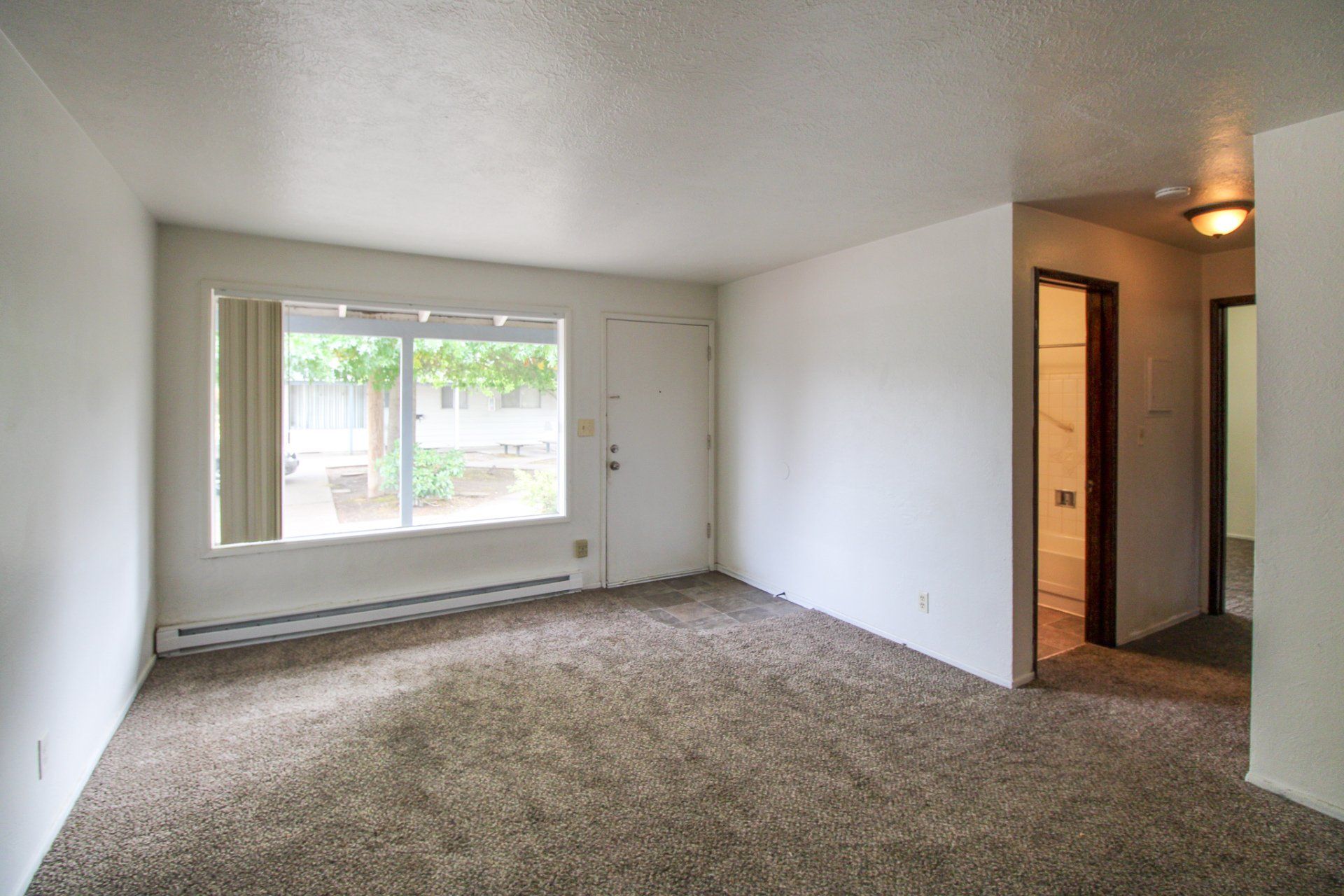An empty living room with a sliding glass door and a window