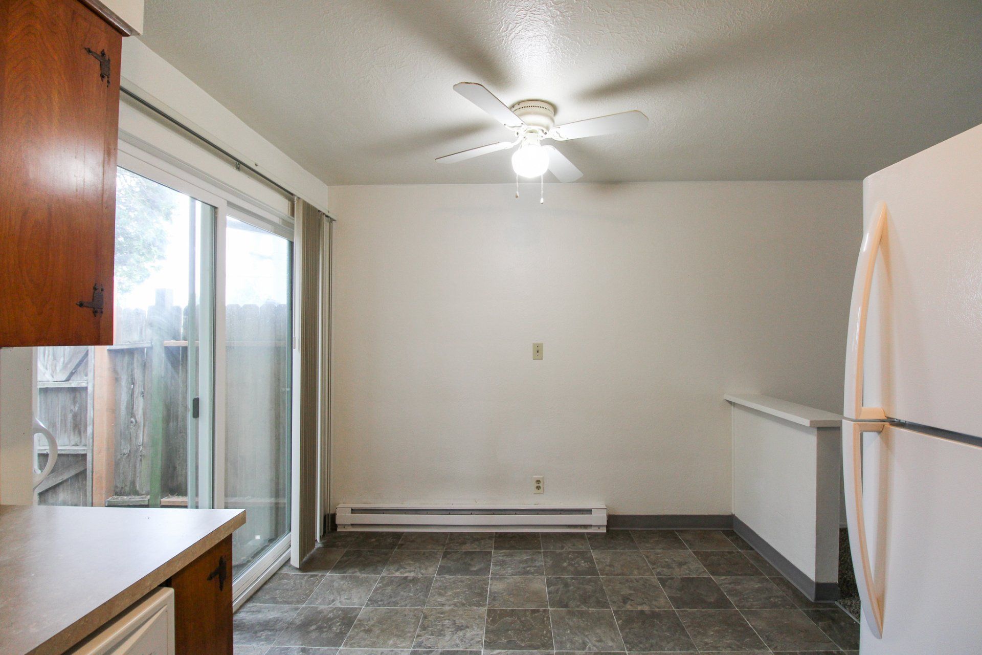 An empty kitchen with a ceiling fan and sliding glass doors