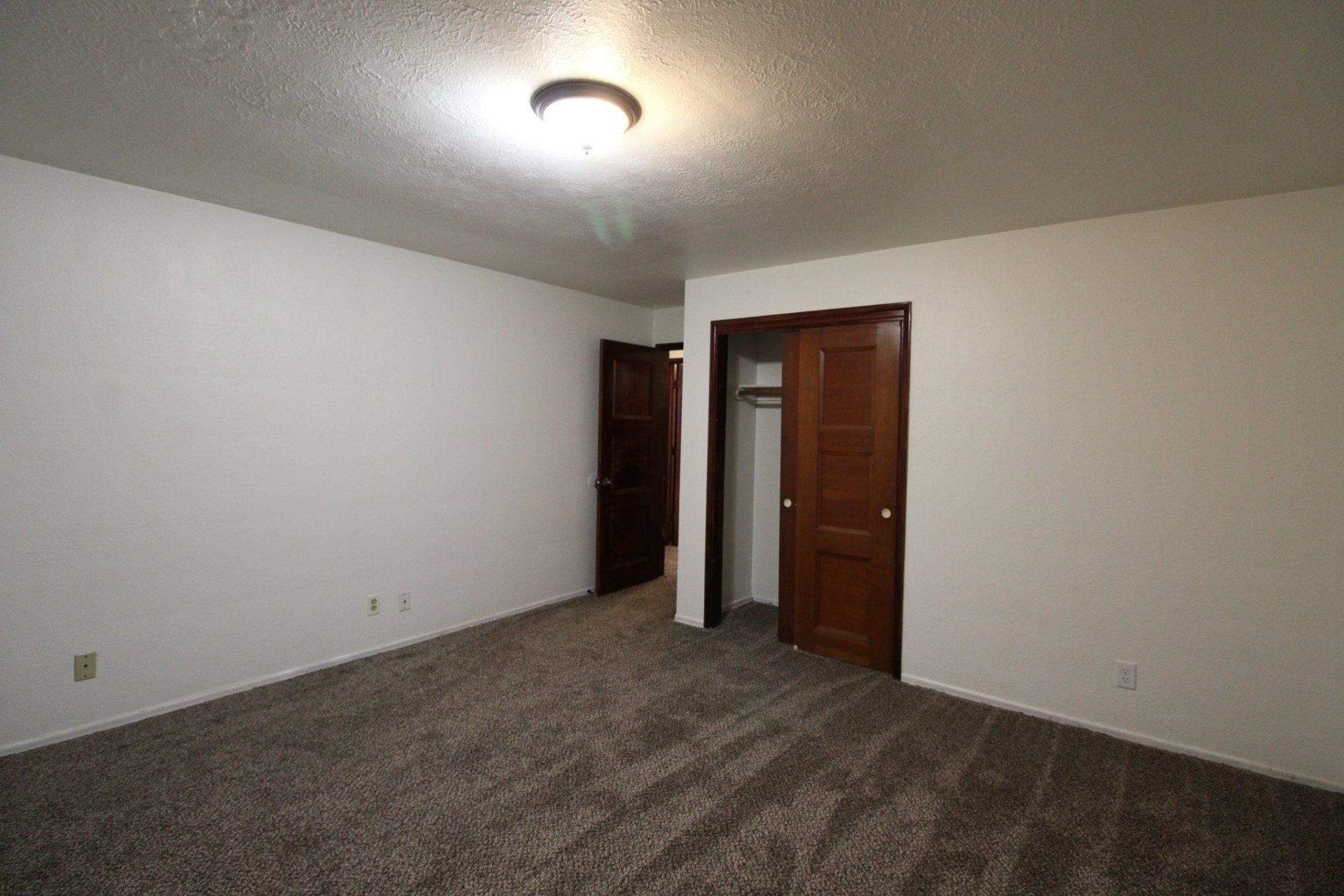 An empty bedroom with a closet and a light on the ceiling.