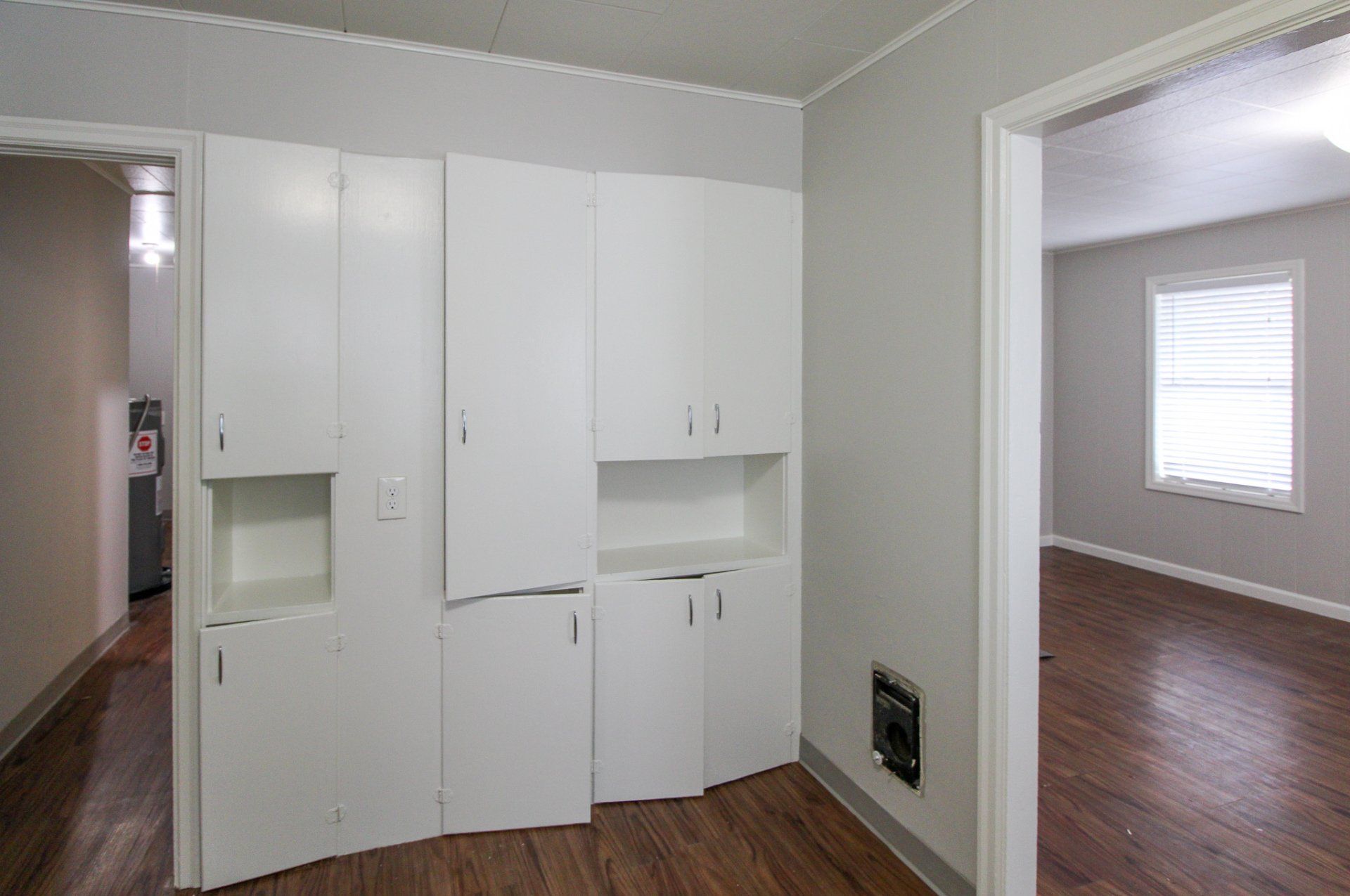 An empty room with white cabinets and hardwood floors in a house.