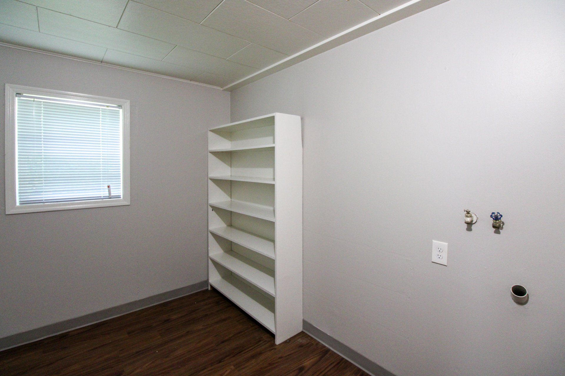 An empty room with a white shelf and a window.