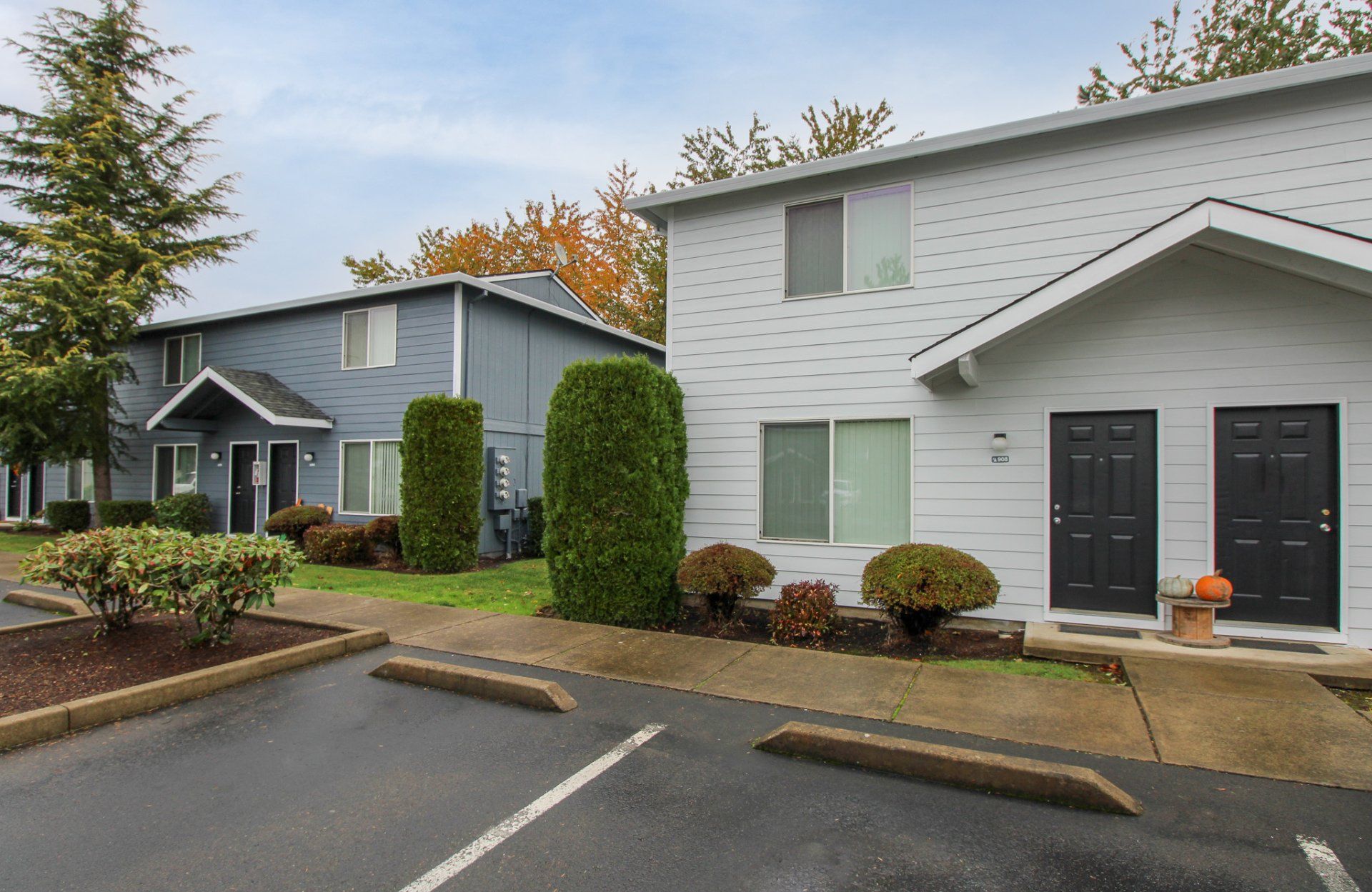 A row of apartment buildings with a parking lot in front of them.