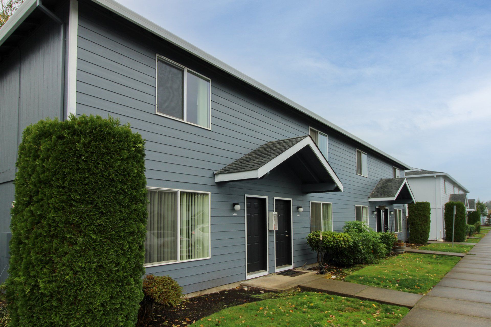 A row of apartment buildings with a sidewalk in front of them