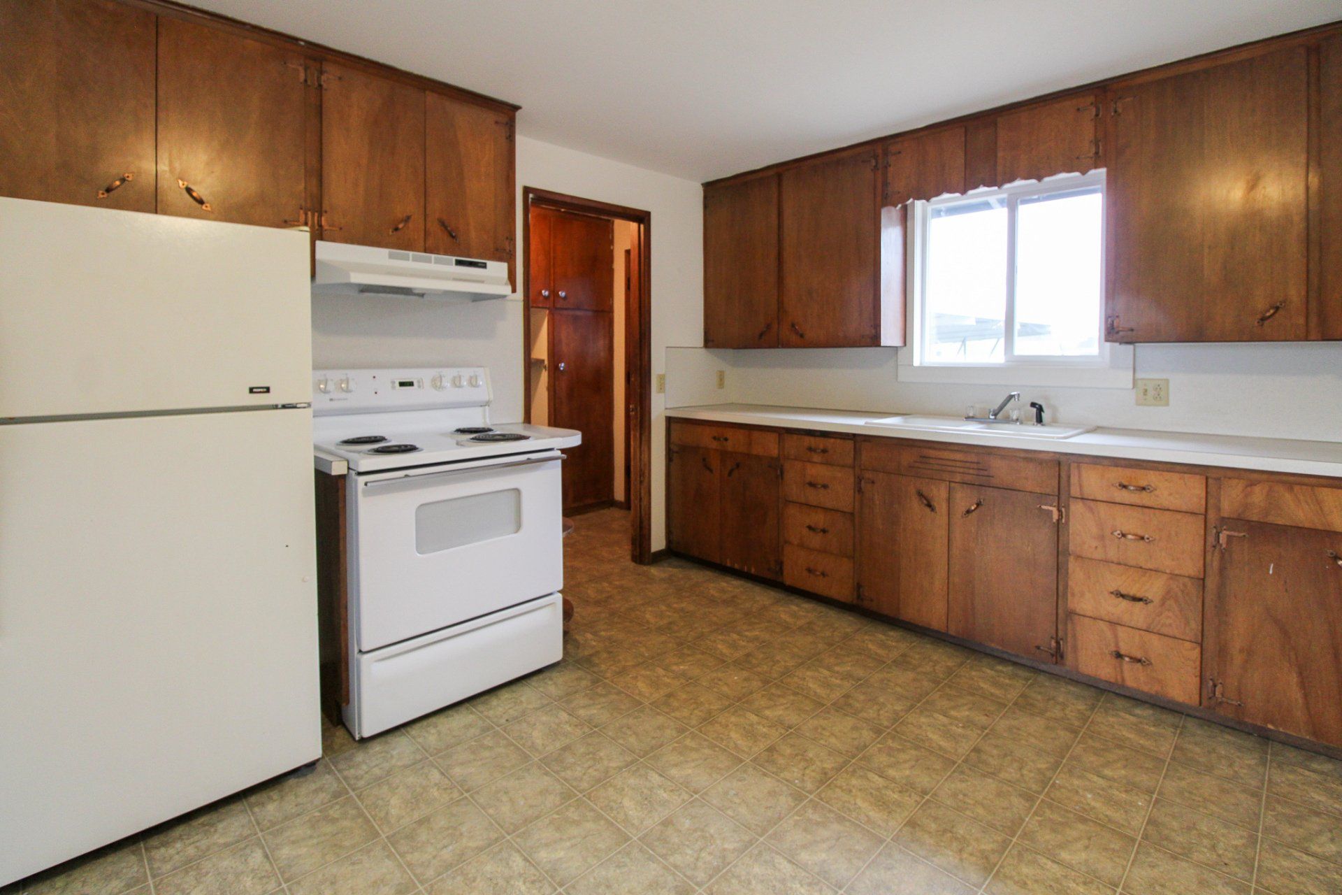 A kitchen with wooden cabinets and a white refrigerator