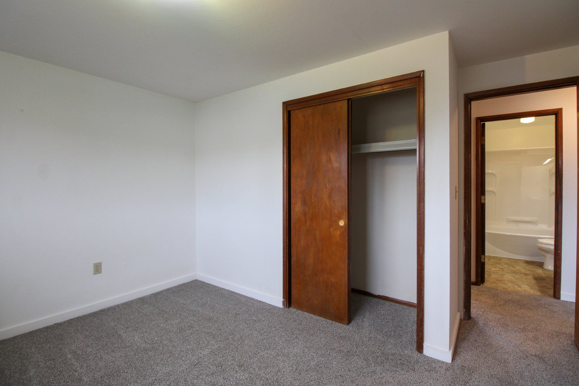 An empty bedroom with a closet and a bathroom.