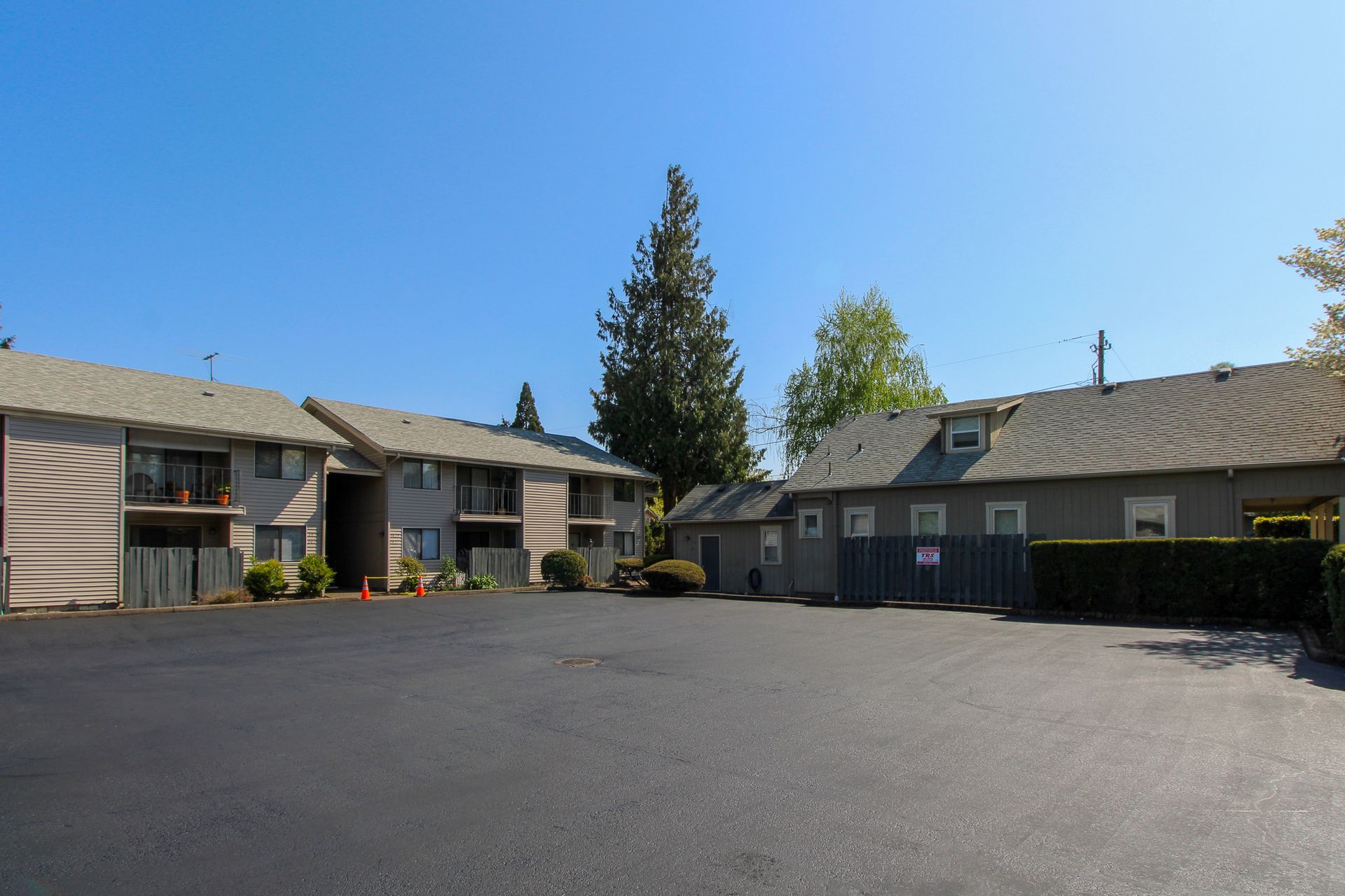 A row of apartment buildings with a large parking lot in front of them.