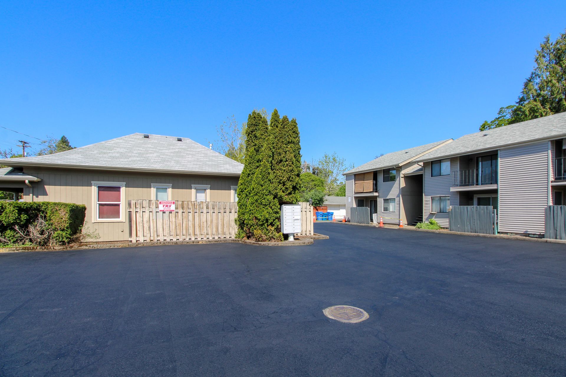 A row of apartment buildings with a large parking lot in front of them.