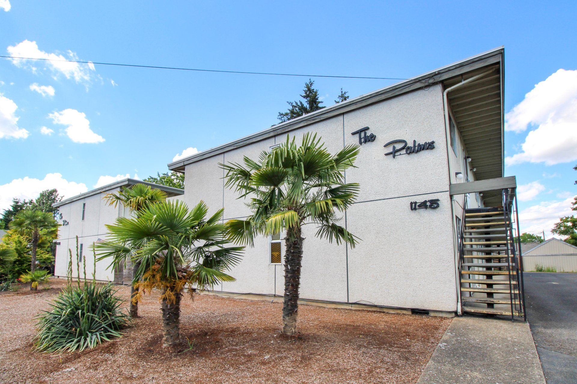 A white apartment building with palm trees in front of it