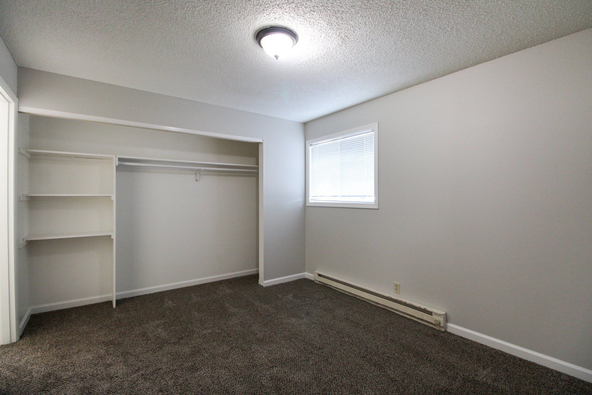 An empty bedroom with a large closet and a window.