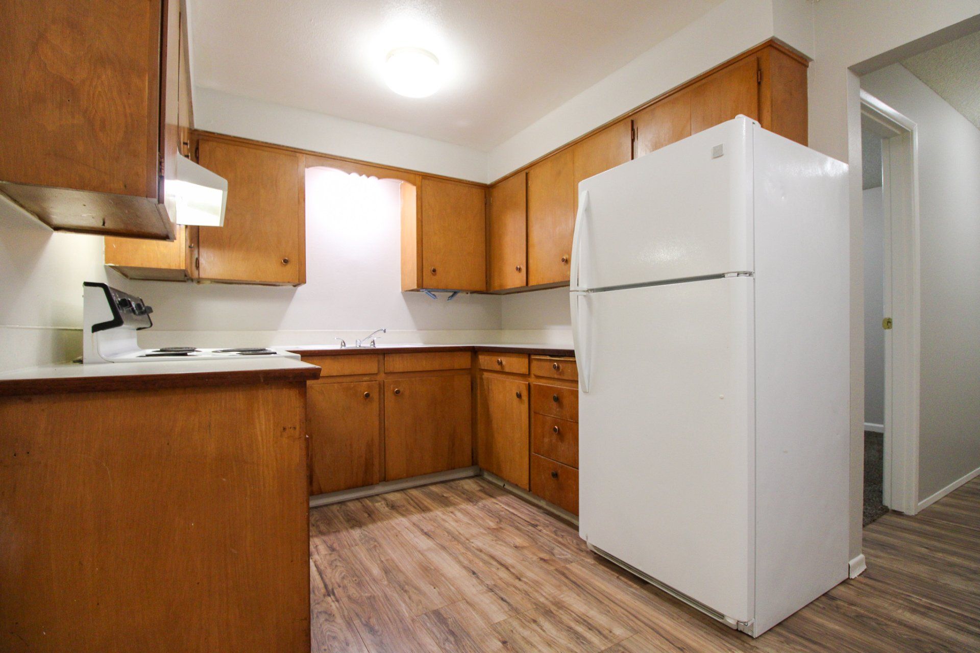 A kitchen with wooden cabinets and a white refrigerator.