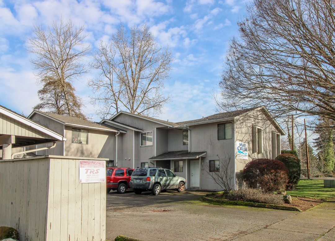 A large apartment building with cars parked in front of it.