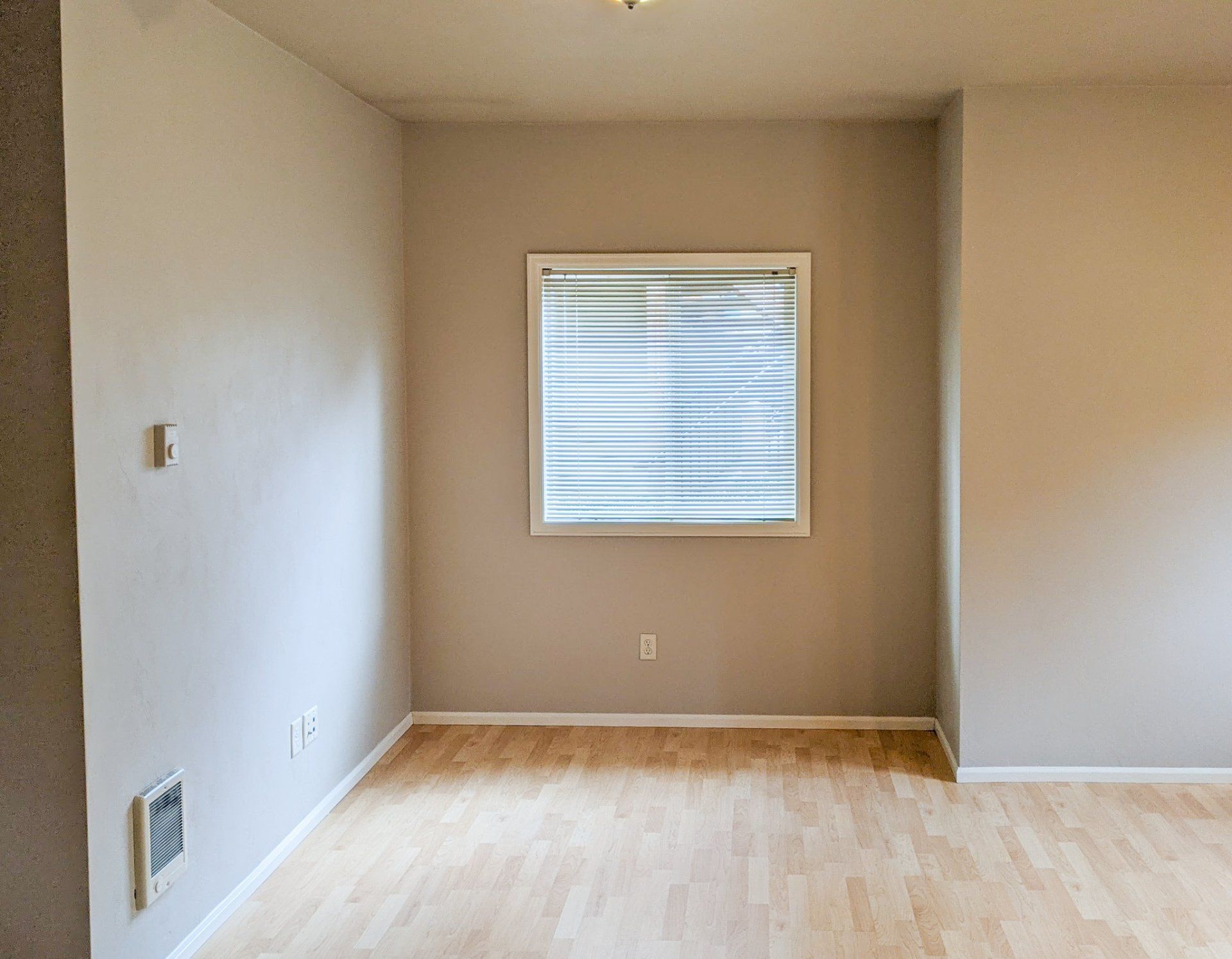 An empty room with hardwood floors and a window.