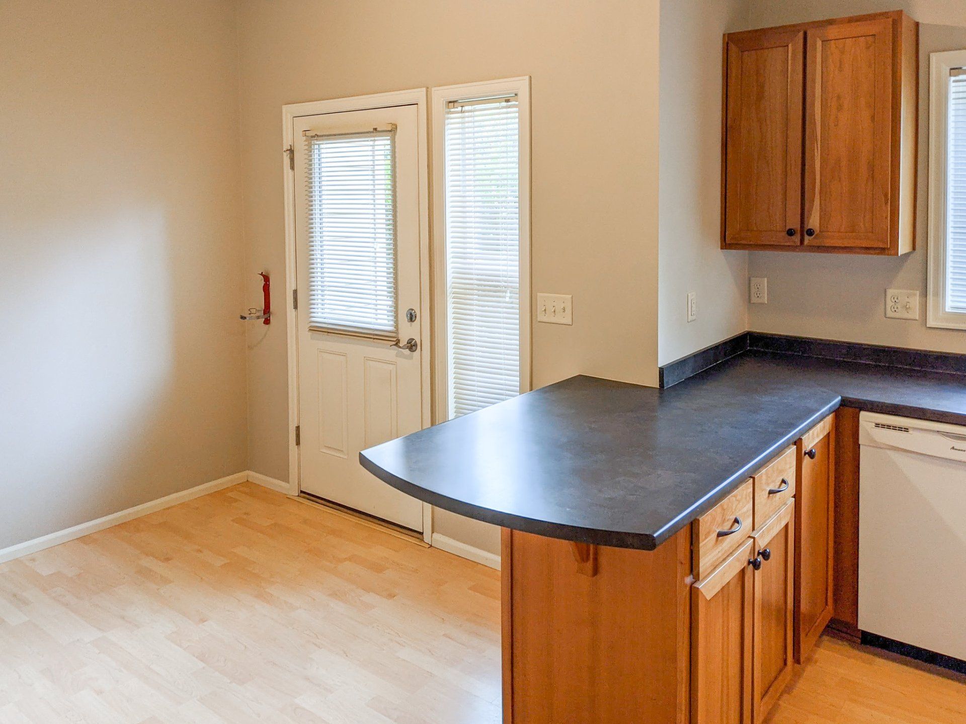 An empty kitchen with wooden cabinets and a black counter top.