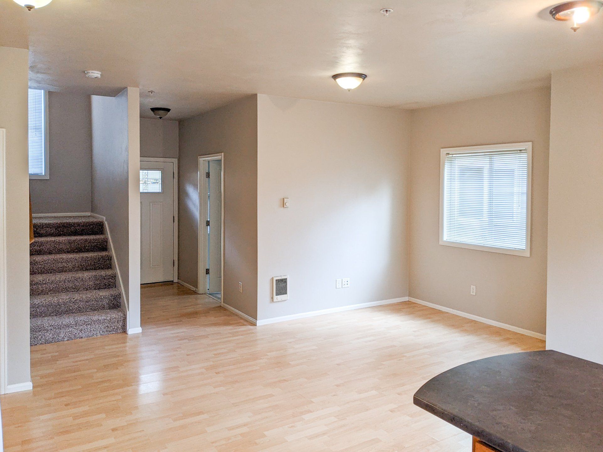 An empty living room with hardwood floors and stairs leading up to the second floor.