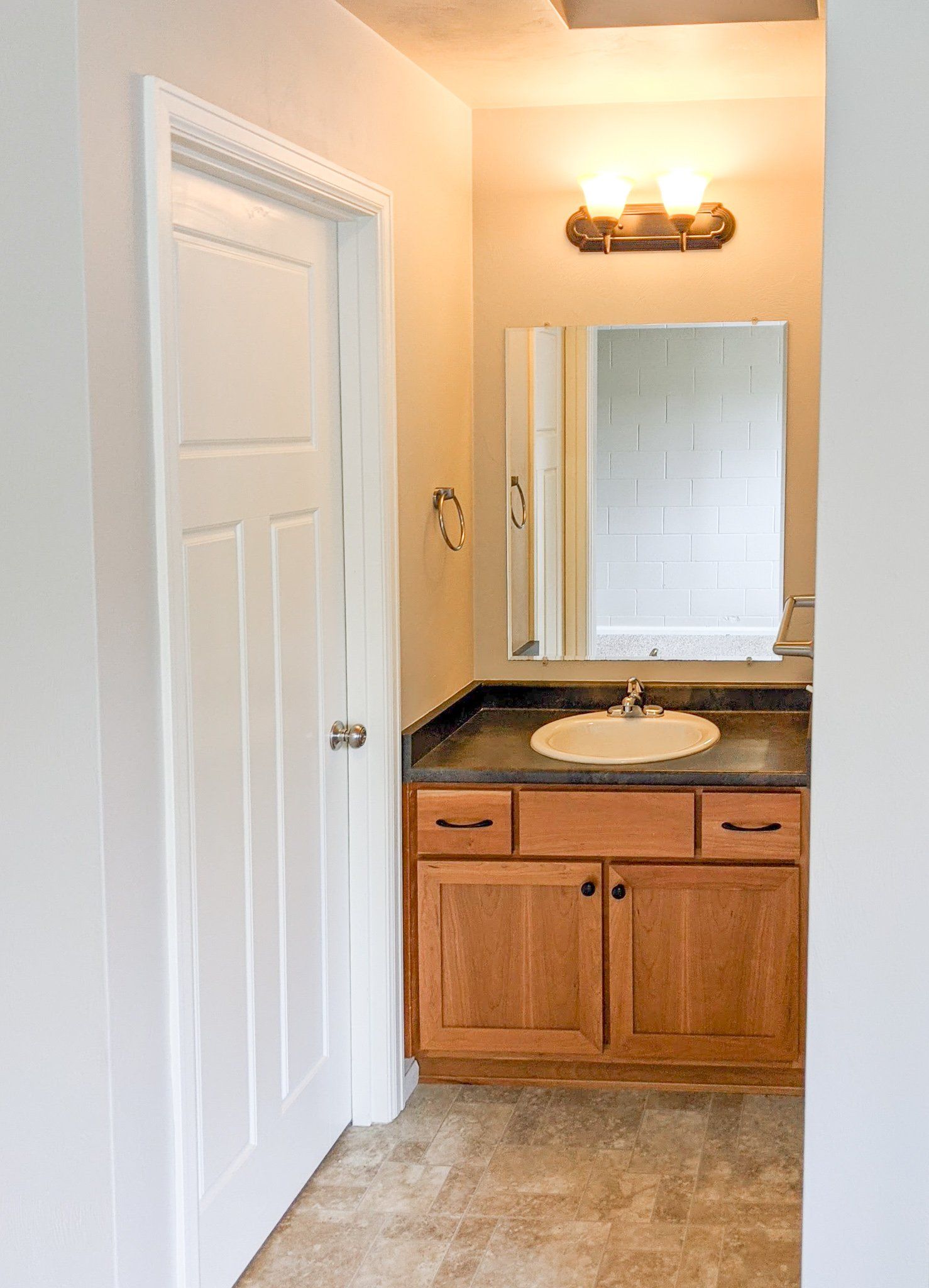 A bathroom with a sink , mirror and cabinets.