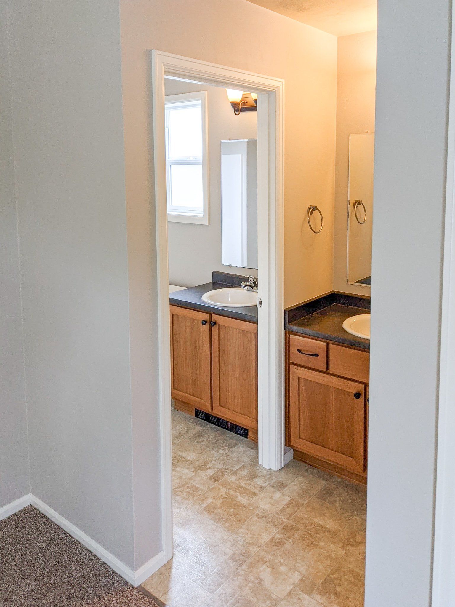 A bathroom with wooden cabinets , a sink and a mirror.