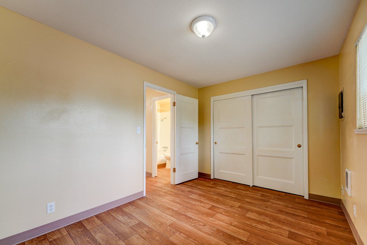 An empty bedroom with hardwood floors and a closet.
