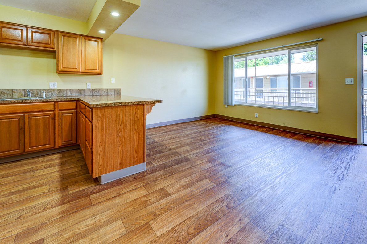 An empty kitchen with wooden cabinets and hardwood floors.