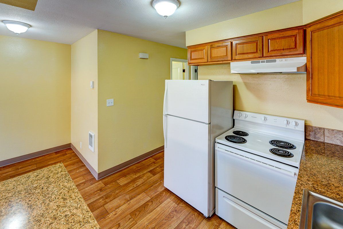 A kitchen with a stove , refrigerator , and sink.