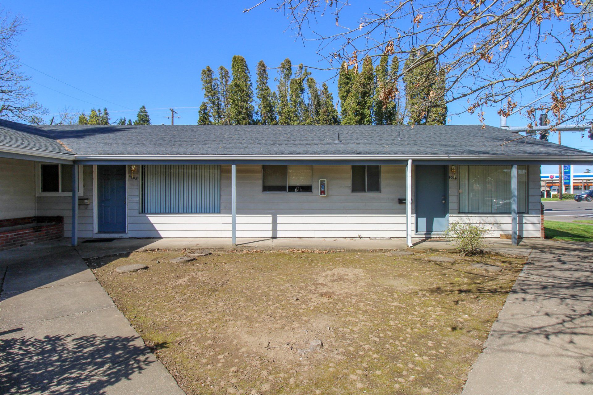 A white house with a porch and trees in the background.