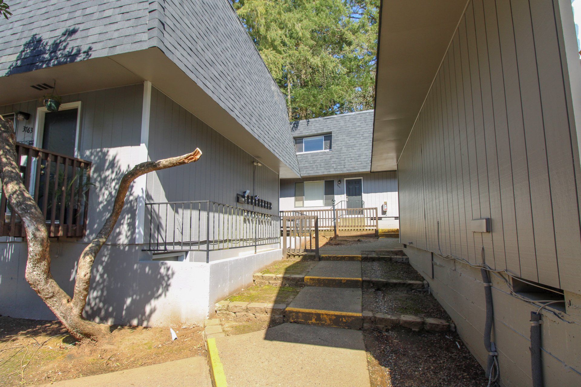 A building with stairs leading up to it and a tree in front of it.