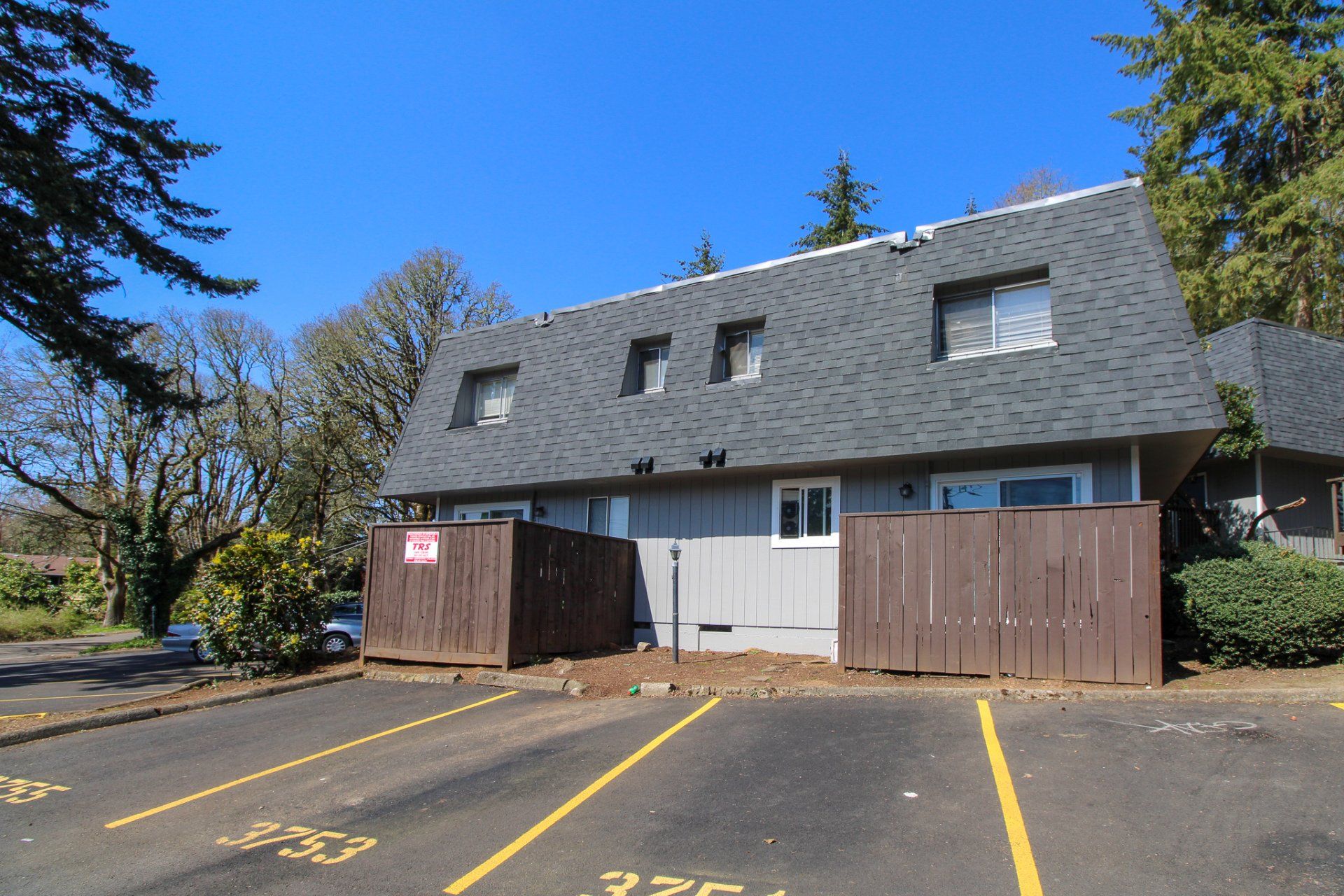 A house with a fence and a parking lot in front of it
