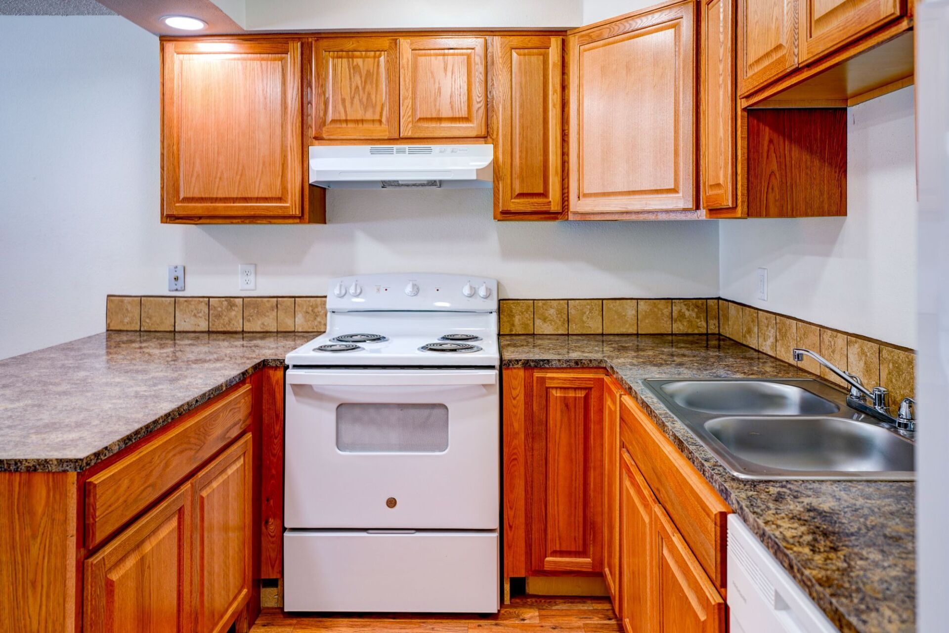 A kitchen with wooden cabinets , a stove and a sink.